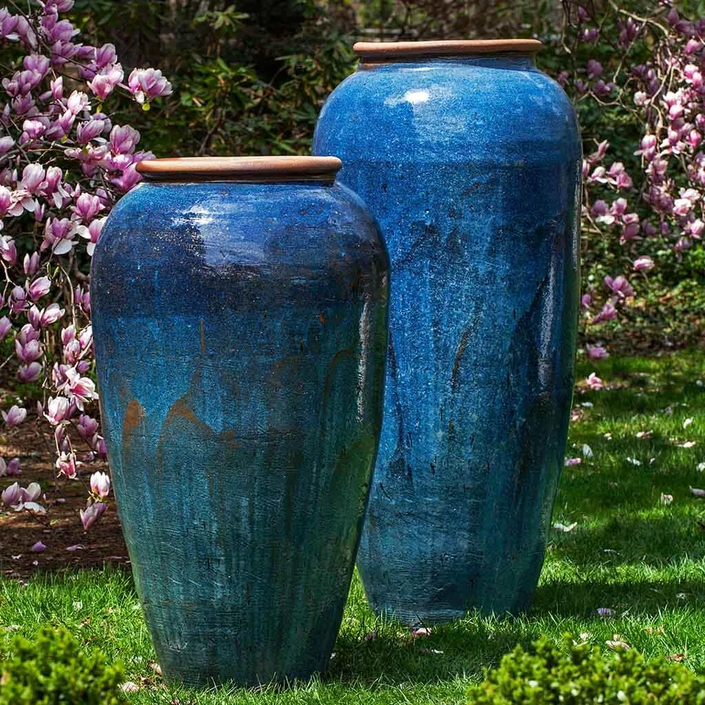 Tall blue planters in a flowering garden
