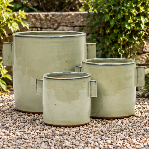 Three pale green cylindrical planters with rectangular side handles